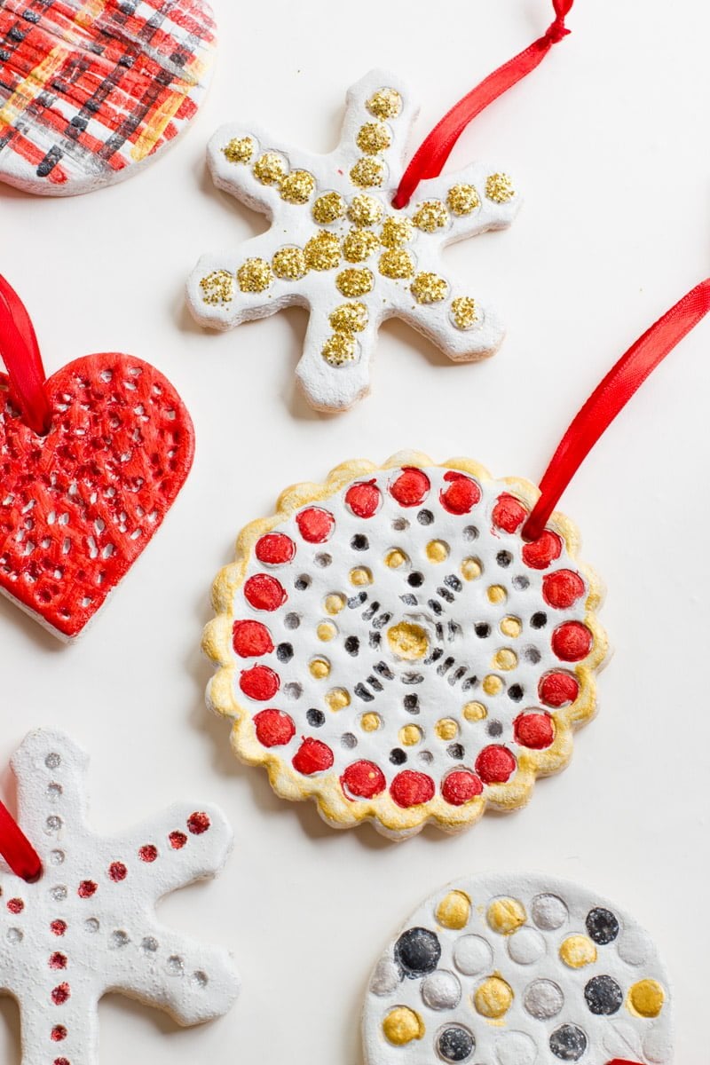 Multiple salt dough ornaments painted in gold, red, and black lie flat on a white background.