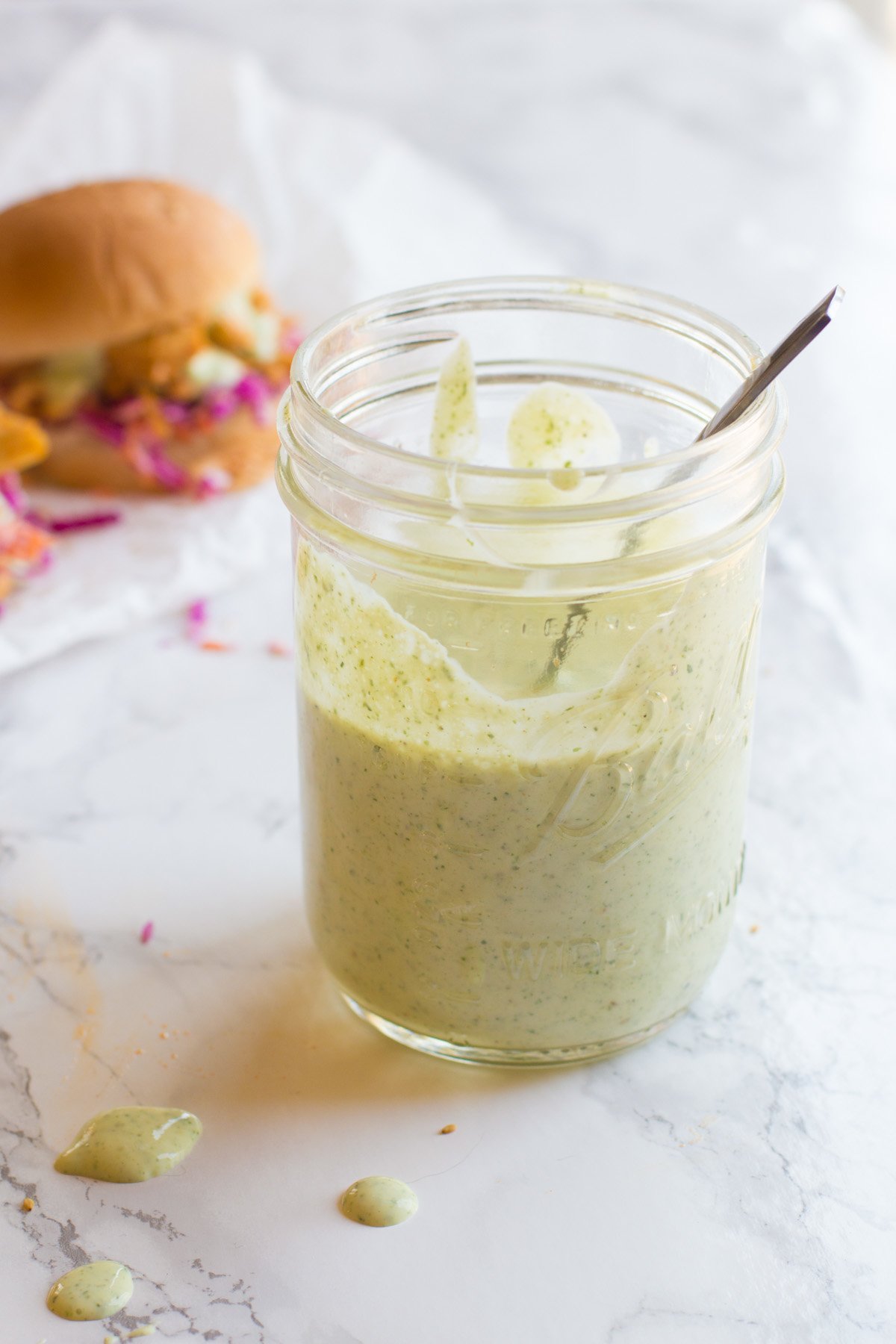 A spoon rests inside a mason jar filled with homemade ranch sauce.