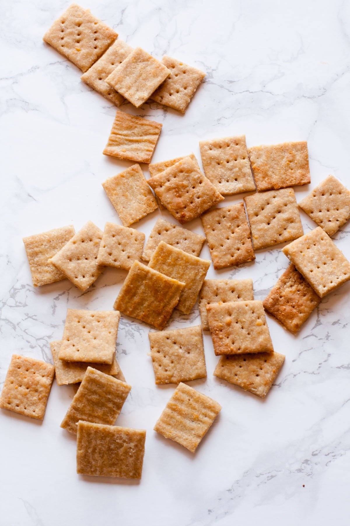 Whole Wheat Parmesan Crackers arranged on a marbled background