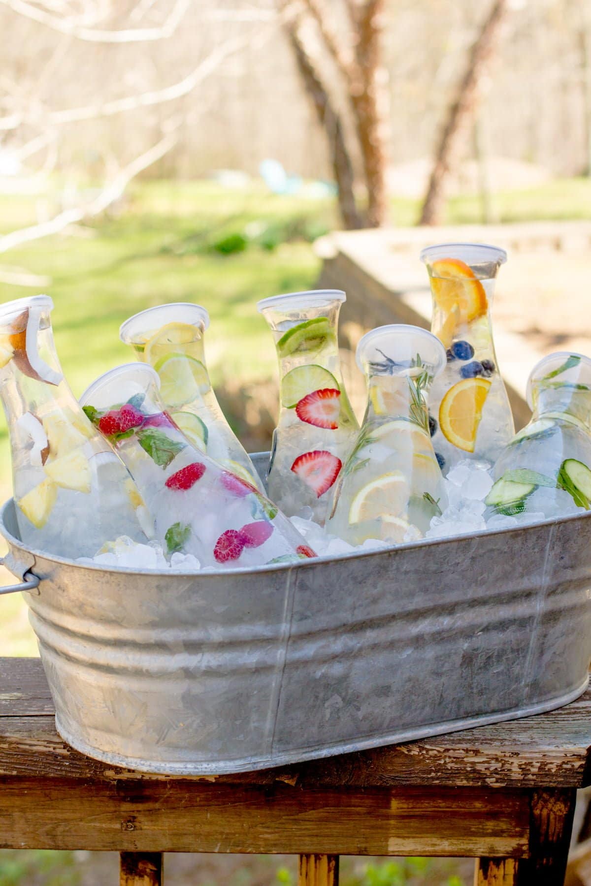 Close-up of carafes filled with different fruit-infused waters sitting in a metal trough filled with ice.