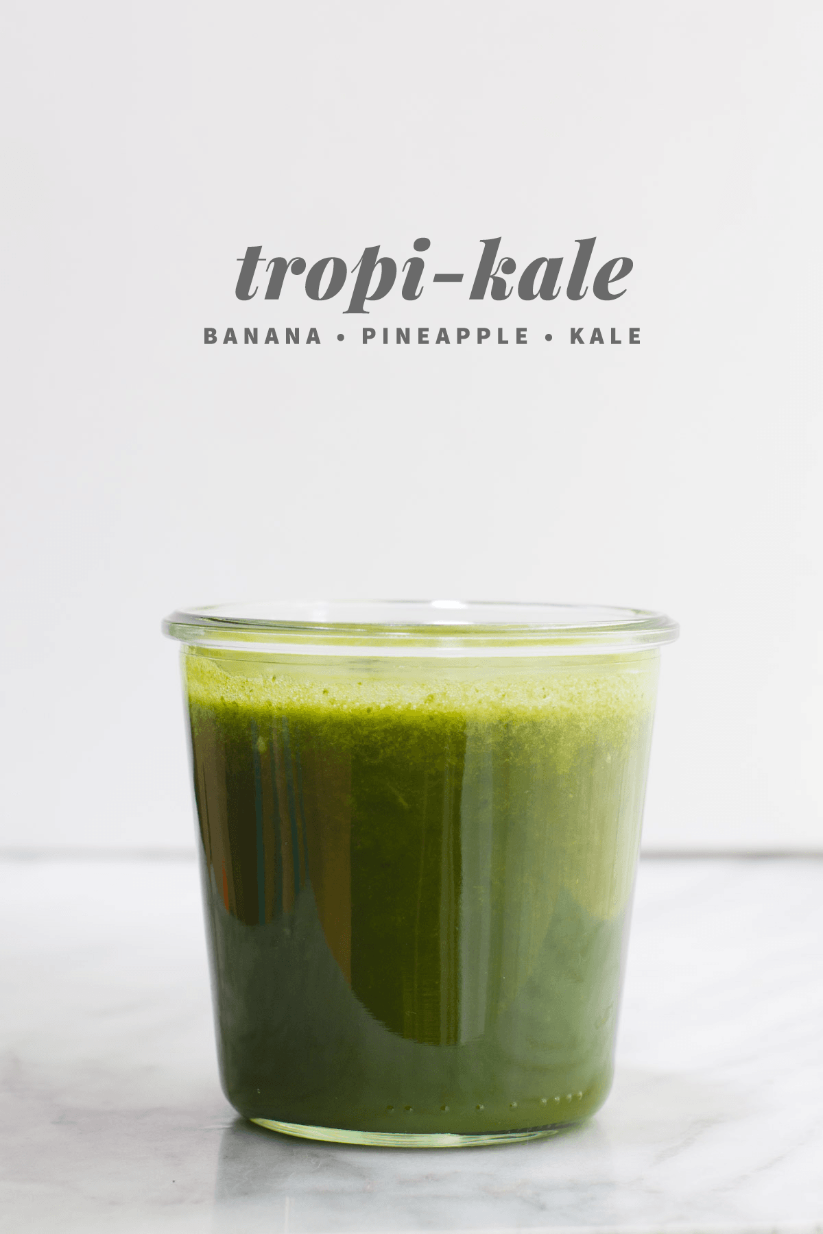 A glass of Tropi-Kale green smoothie, a standout among juice recipes, made with banana, pineapple, and kale.