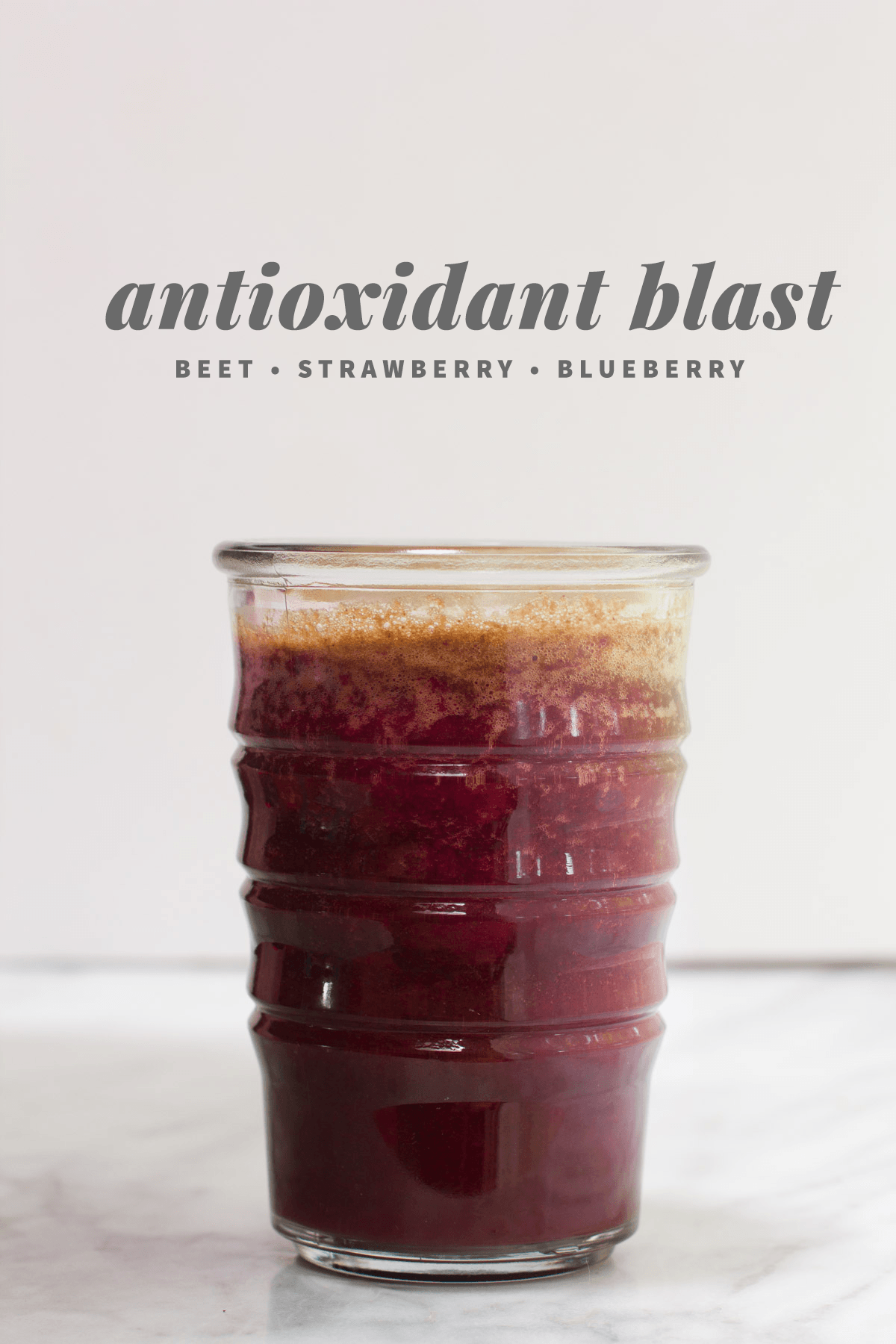 A glass of dark red beet, strawberry, and blueberry smoothie with the text antioxidant blast above it, perfect for healthy juice recipes.