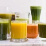 Glasses of varying heights filled with fruit and vegetable juices.