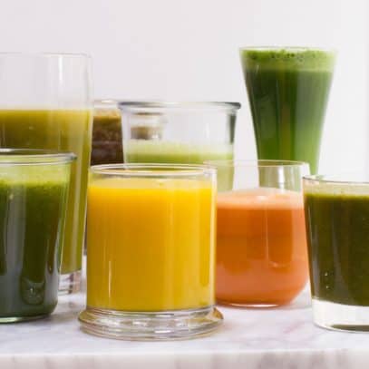 Glasses of varying heights filled with fruit and vegetable juices.