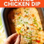 A hand hold up a chip loaded with crackpot buffalo chicken dip. A text overlay reads "Slow Cooker Buffalo Chicken Dip."