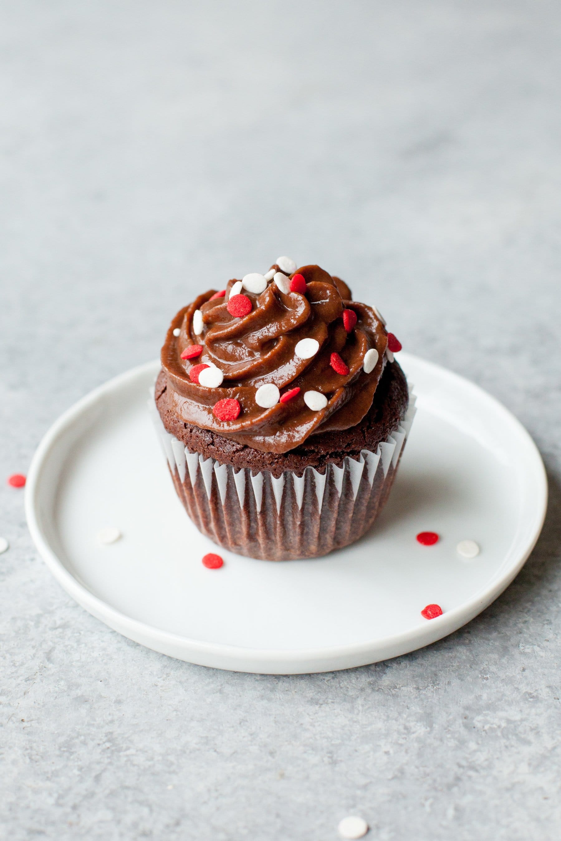 A healthier chocolate cupcake sits on a white plate.