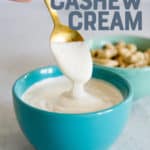 Spoon drizzling cashew cream into a turquoise bowl full of more cashew cream. A text overlay reads "Vegan Cashew Cream. Use it to replace all kinds of dairy!"