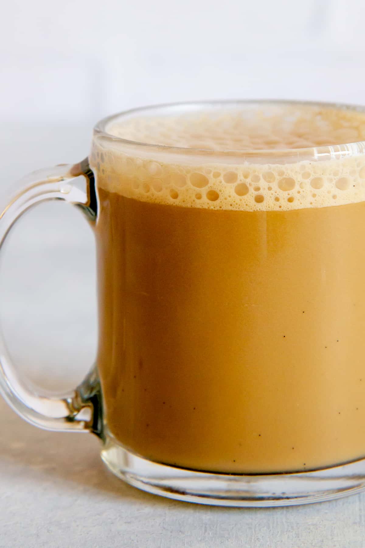 Close-up on a coffee with cashew coffee creamer in a clear glass mug.