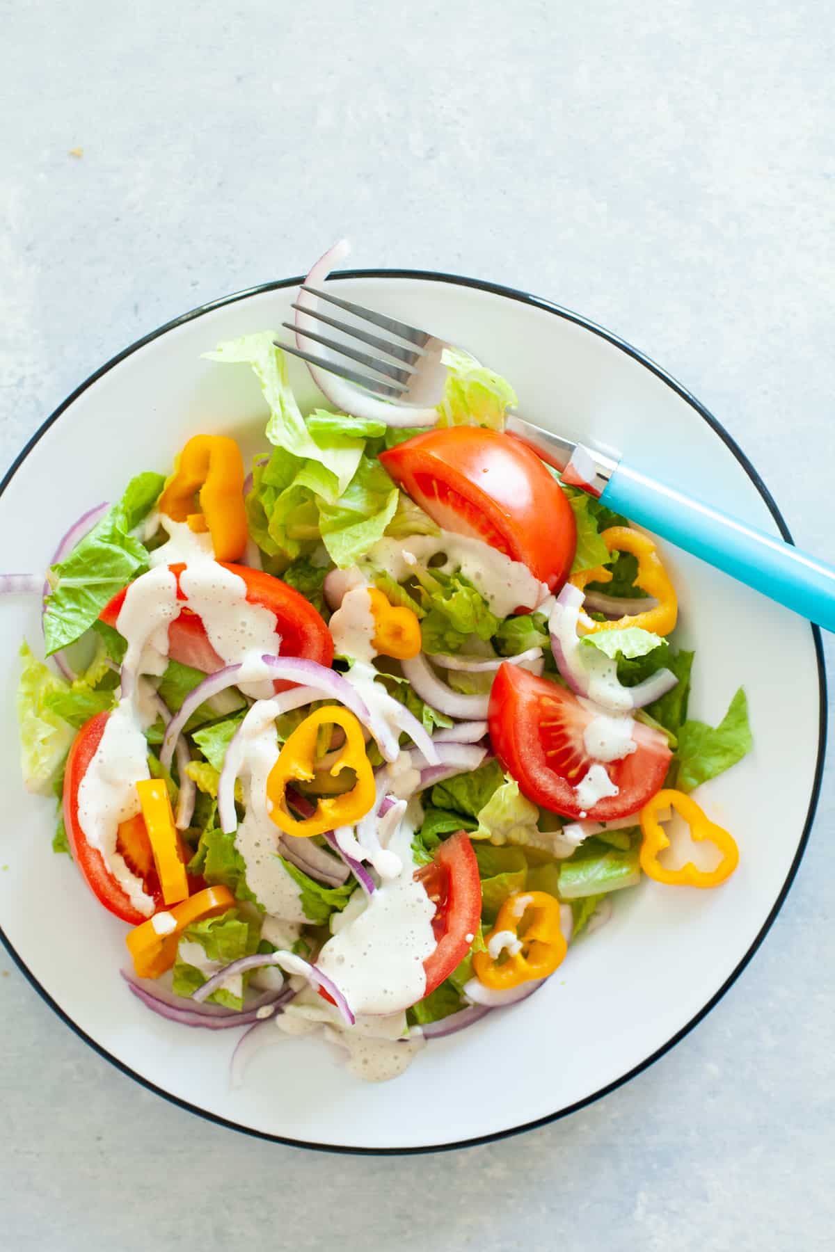 A white bowl is filled with a colorful salad dressed with paleo cashew ranch dressing.