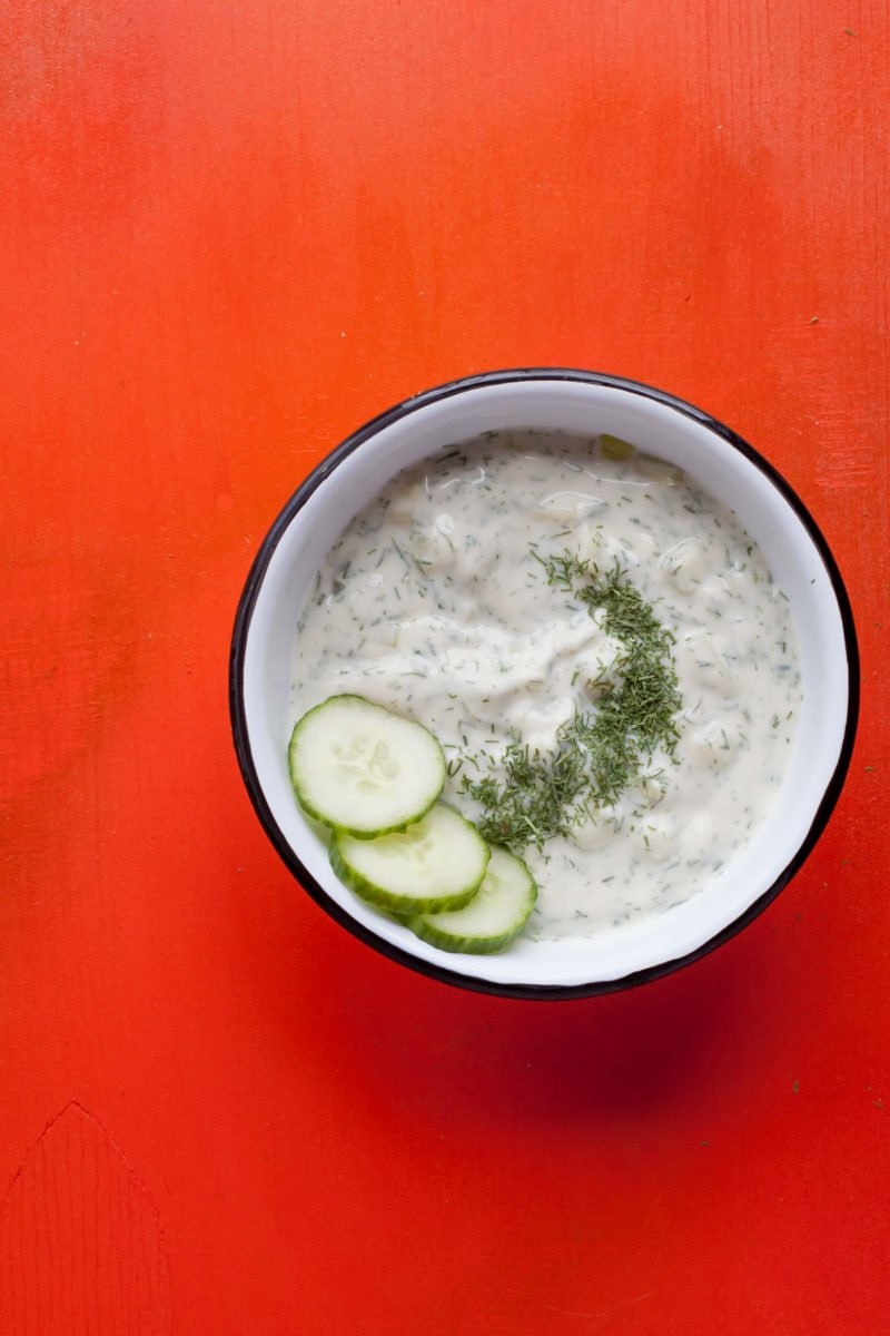 Finished Tzatziki Sauce sits in a bowl on a red background