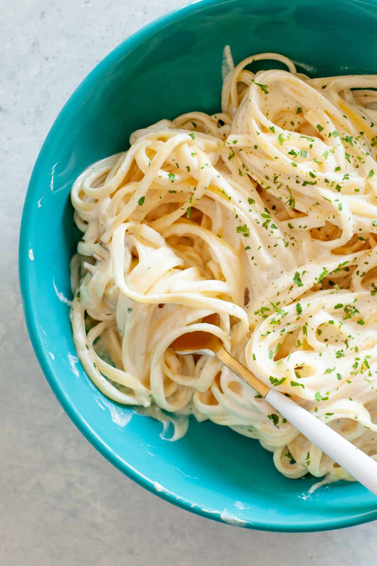 Noodles with vegan alfredo sauce twirled around a fork.