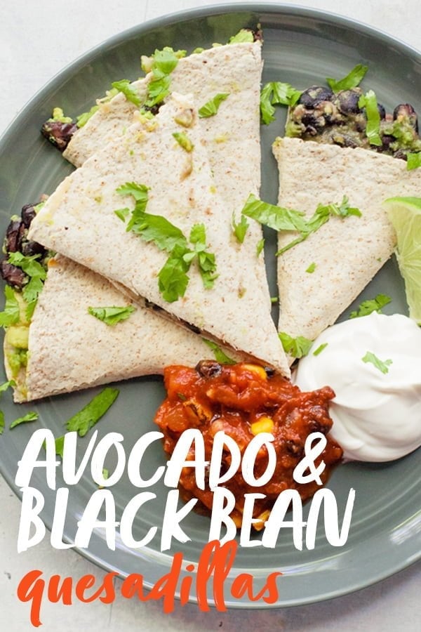 Quesadilla triangles on a gray plate, with a mound of salsa and a mound of sour cream next to them. A text overlay reads "Avocado and Black Bean Quesadillas."