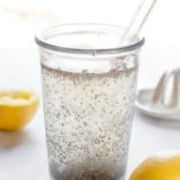 A tall glass with chia seeds floating in water mixed with apple cider vinegar and lemon juice.