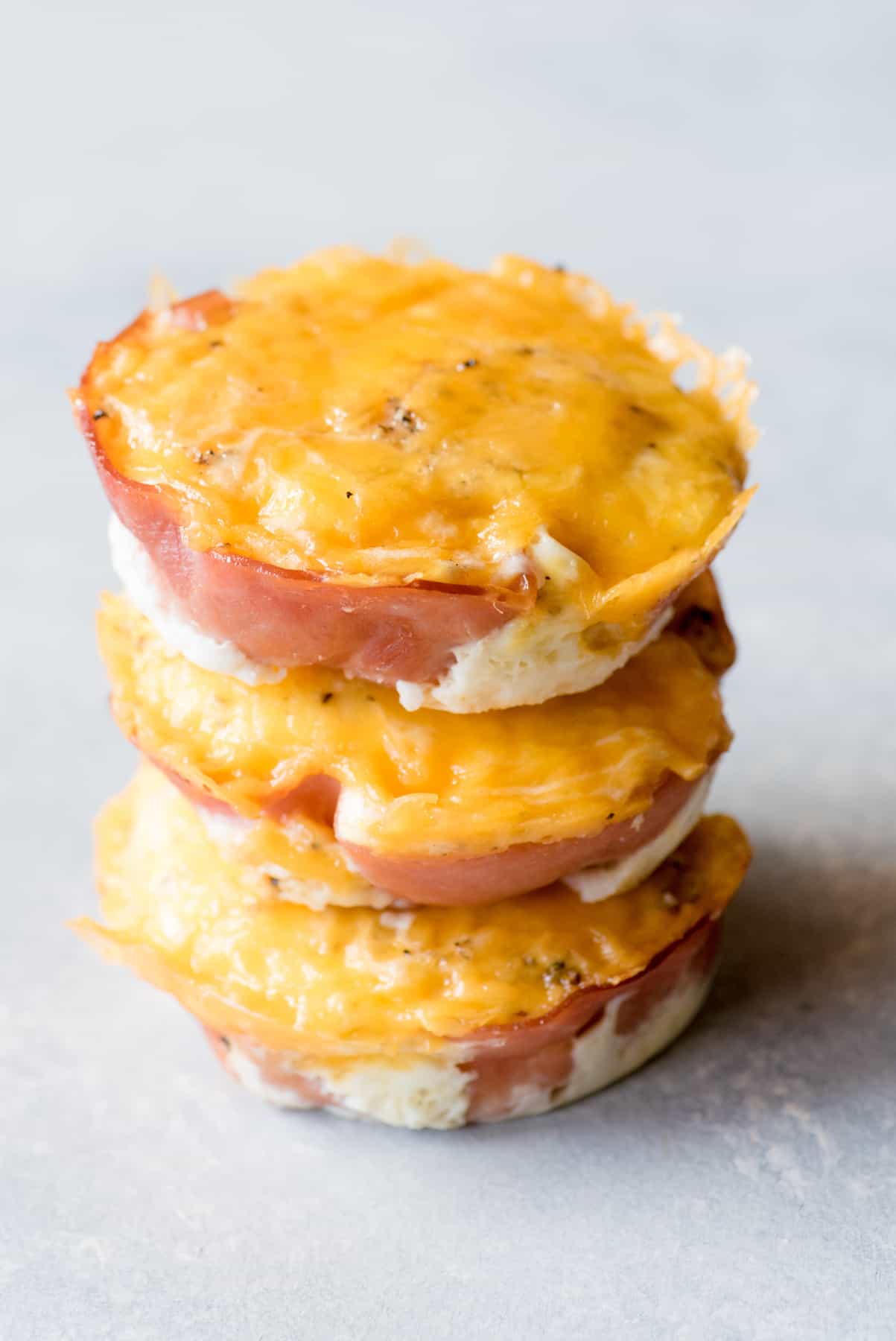 Three egg muffins are stacked on a gray countertop.