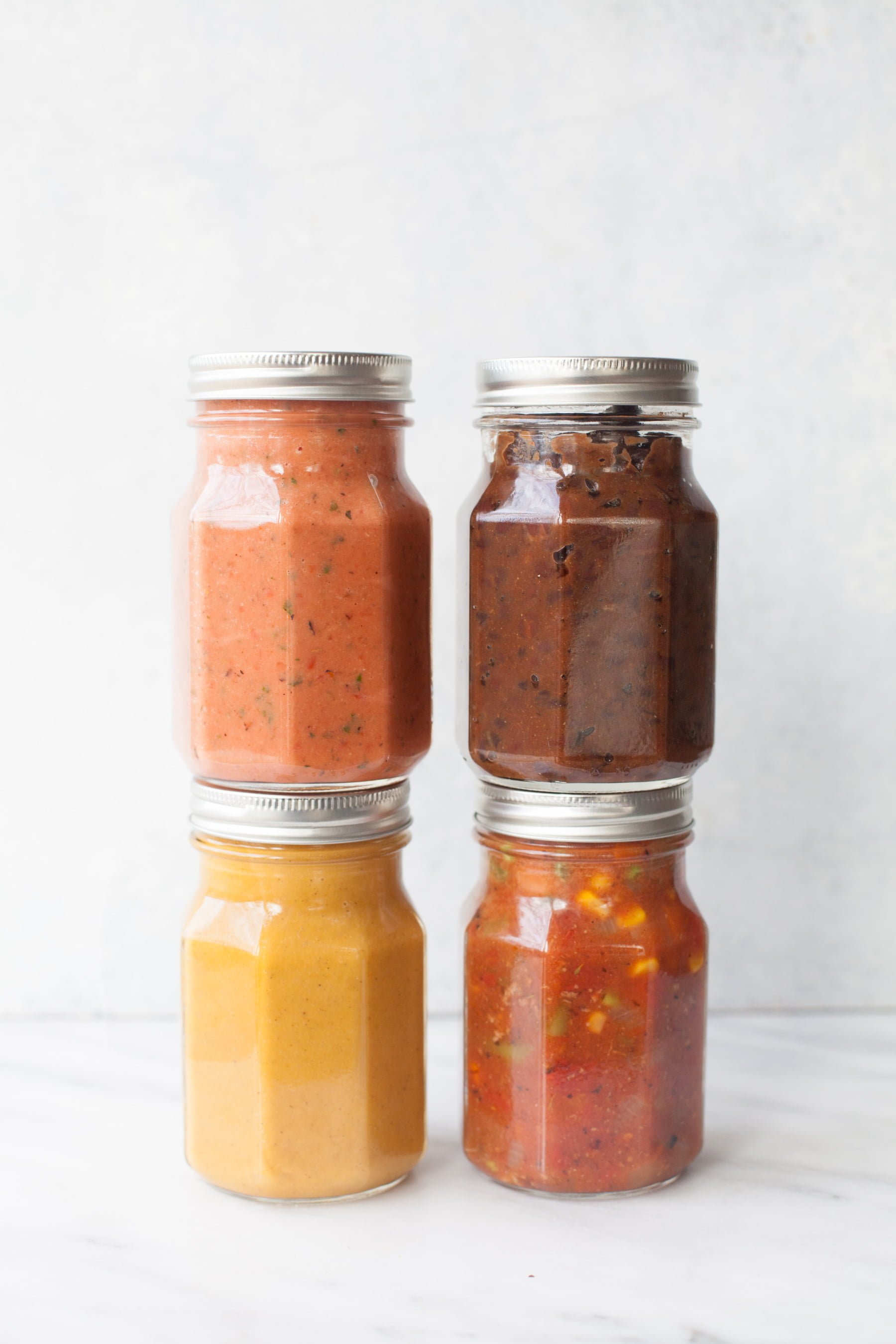 Four glass canning jars stacked with soup in them