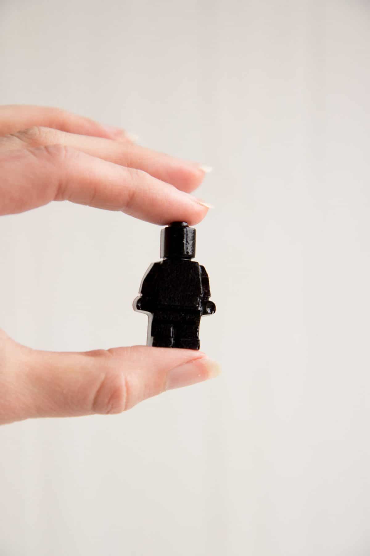 A hand holds a Lego-shaped gummy made from an elderberry syrup recipe.