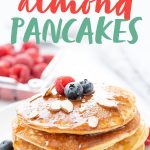 Side angle shot of a stack of grain-free blender almond pancakes, garnished with berries and sliced almonds, with a text overlay
