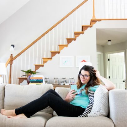 Woman lounging on couch while looking at a phone to find a therapist