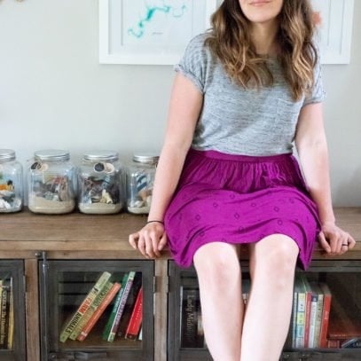 Woman in a gray shirt and purple skirt, sitting on a counter