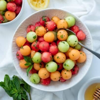 Overhead shot of Honey-Mint Melon Salad in a white bowl with a spoon