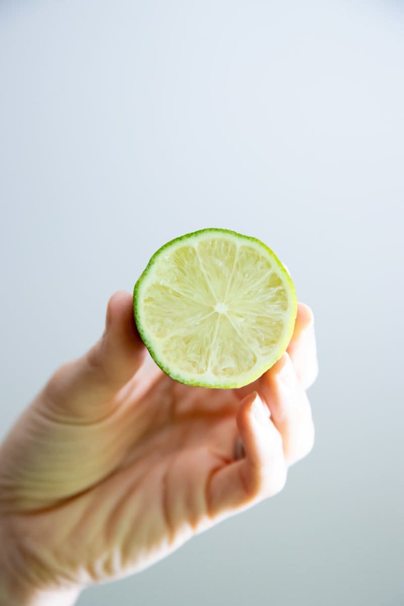 Hand holding a halved lime, with the cut side facing the camera