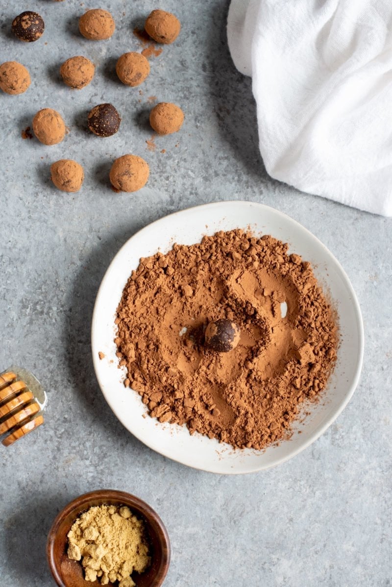 Overhead shot of Ginger Bites (an all-natural upset stomach remedy) being rolled in cocoa powder