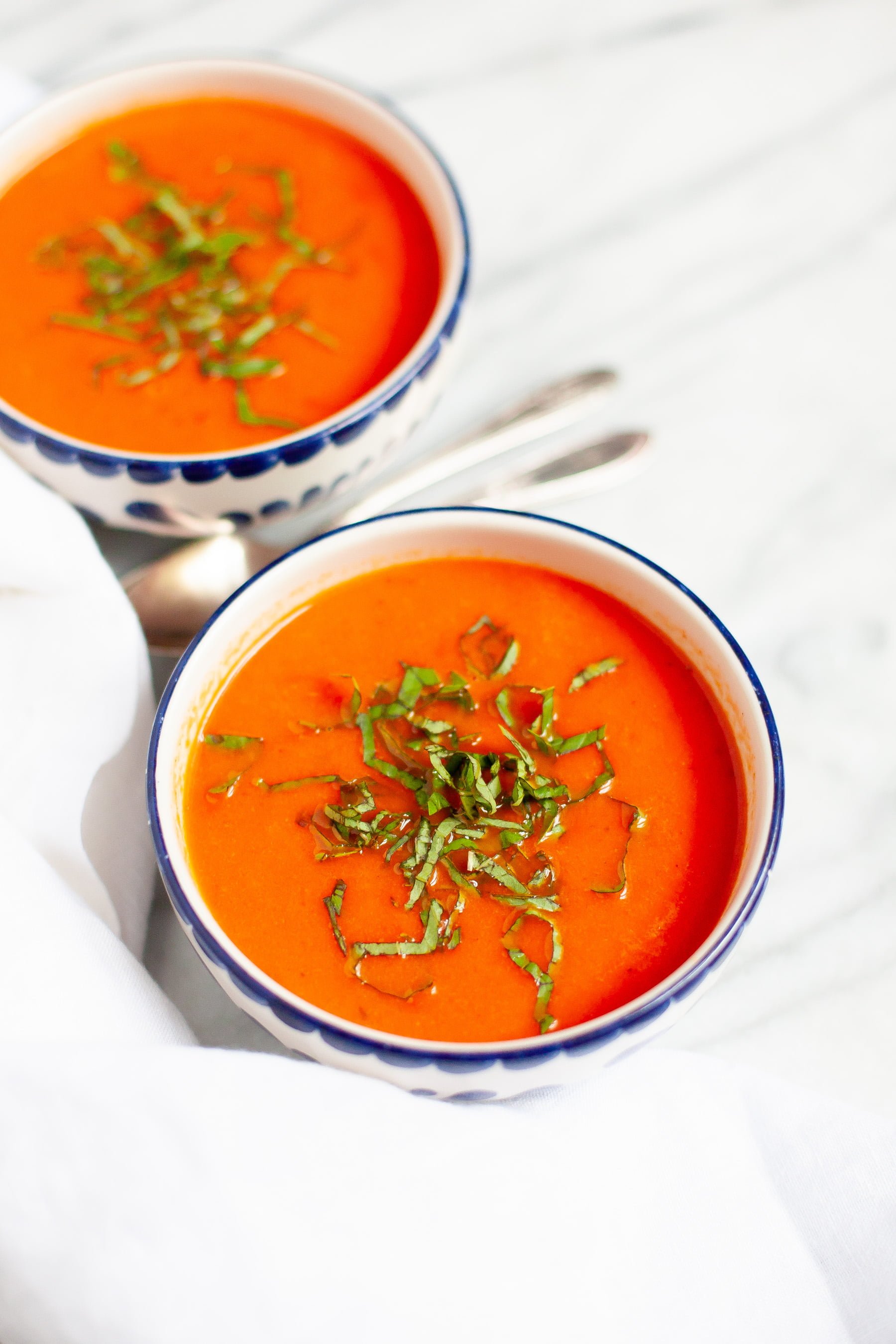 Single angle shot of Garden Fresh Tomato Soup on a white background, with whole tomatoes off to the side