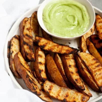 Side angle shot of Perfect Grilled Potato Wedges with a small dish of sauce