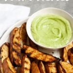 Side angle shot of Perfect Grilled Potato Wedges with a small dish of sauce, with a text overlay