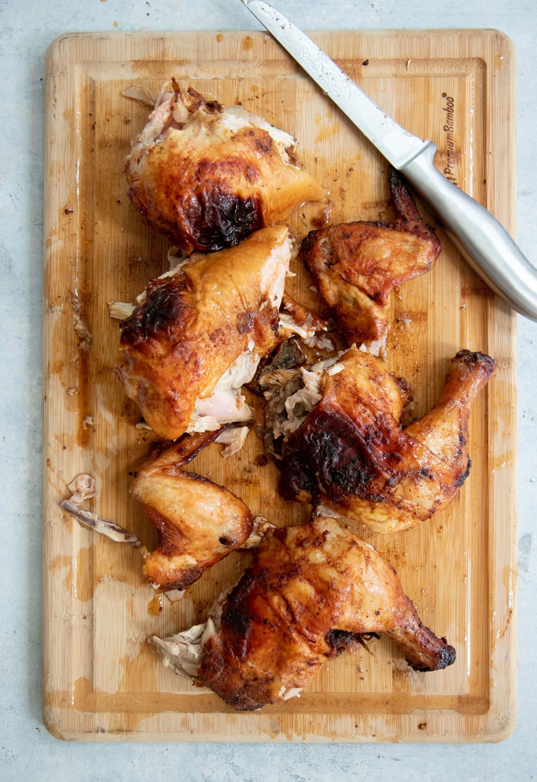 Overhead shot of cut-up grilled chicken on a wooden cutting board