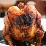 Grilled Beer Can Chicken standing up in a cast iron skillet, with a text overlay