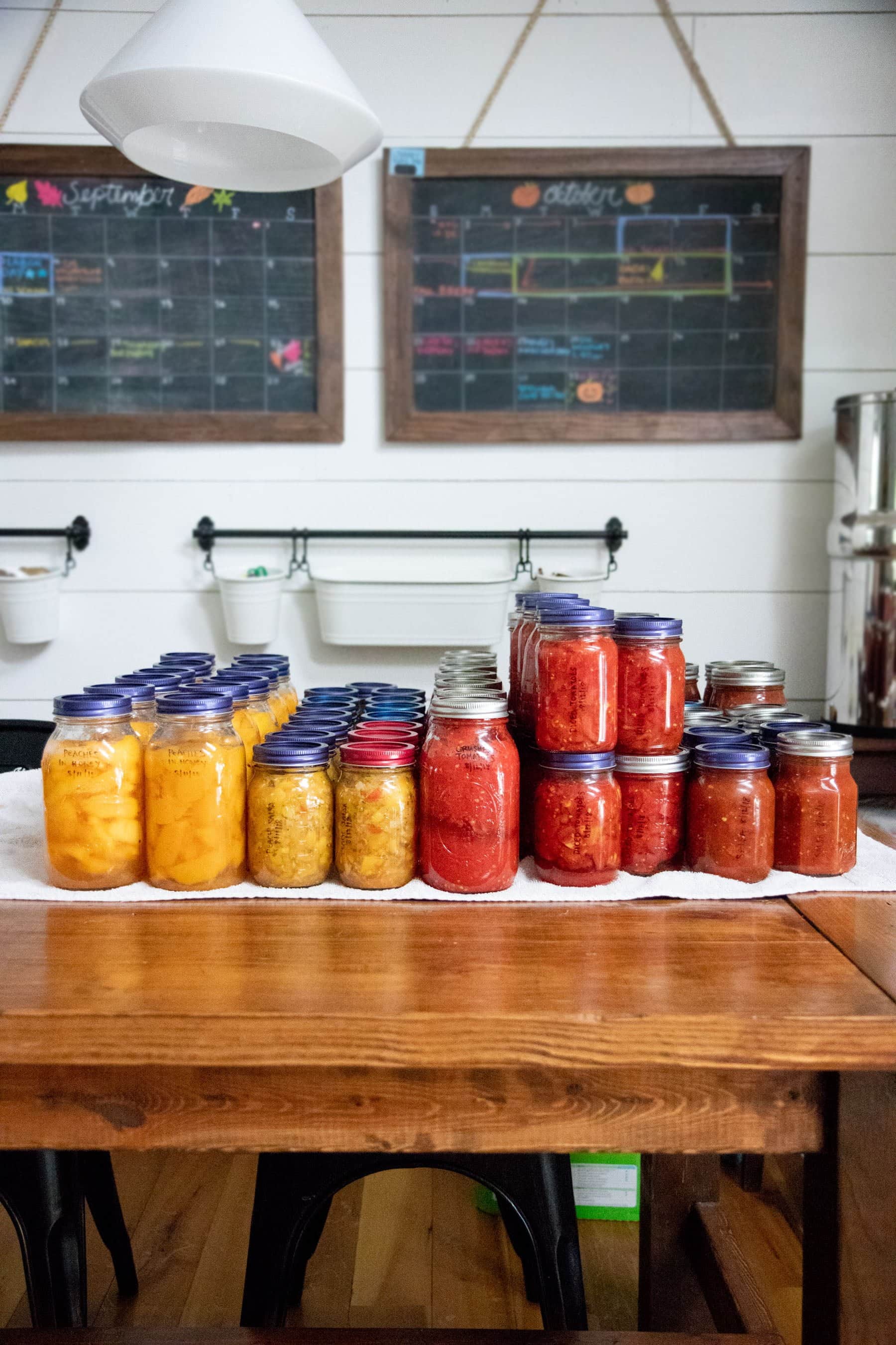 Glass jars of tomatoes and peaches lined up on a table