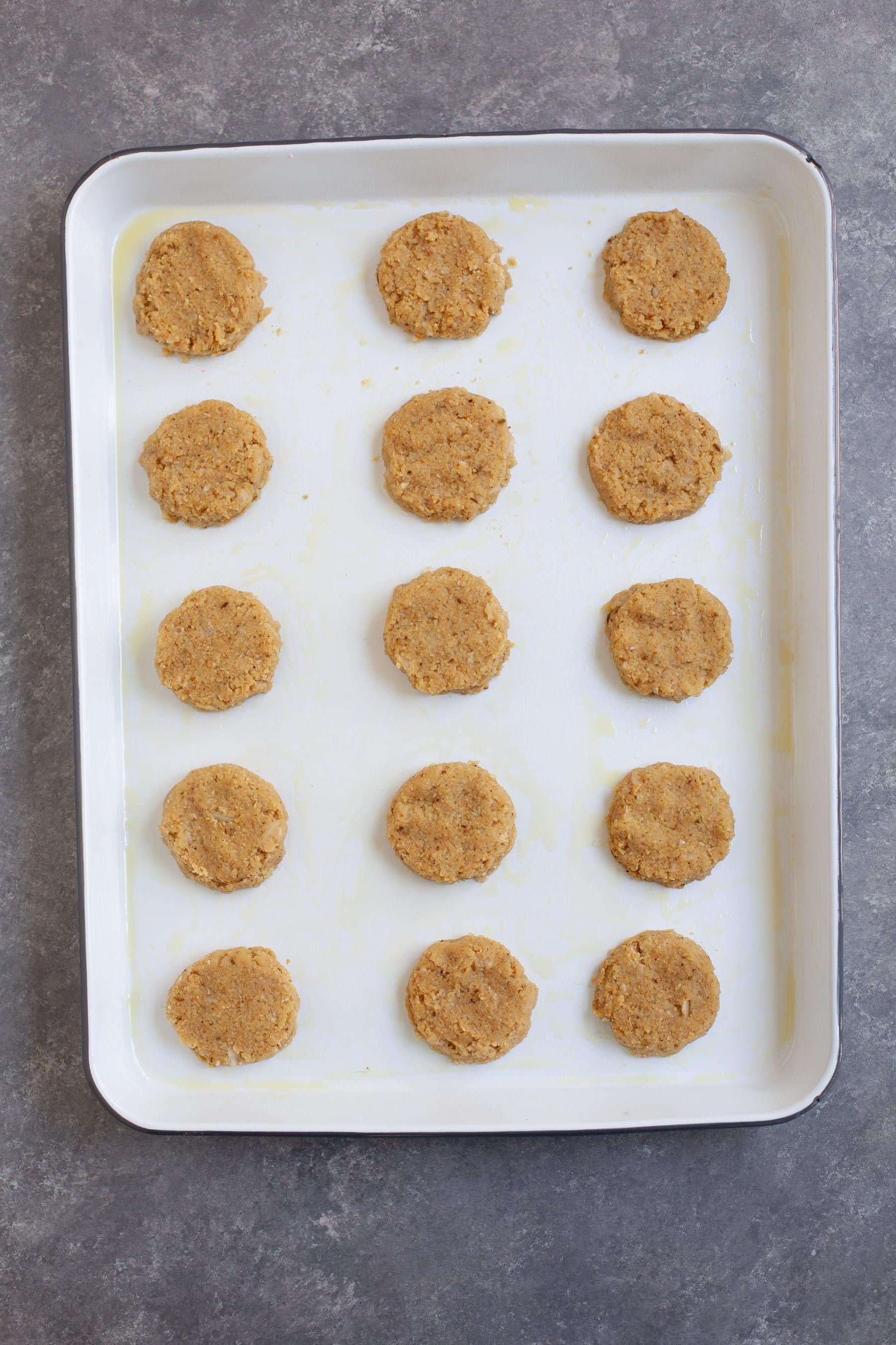 Falafel patties lined up on a baking dish, ready for cooking