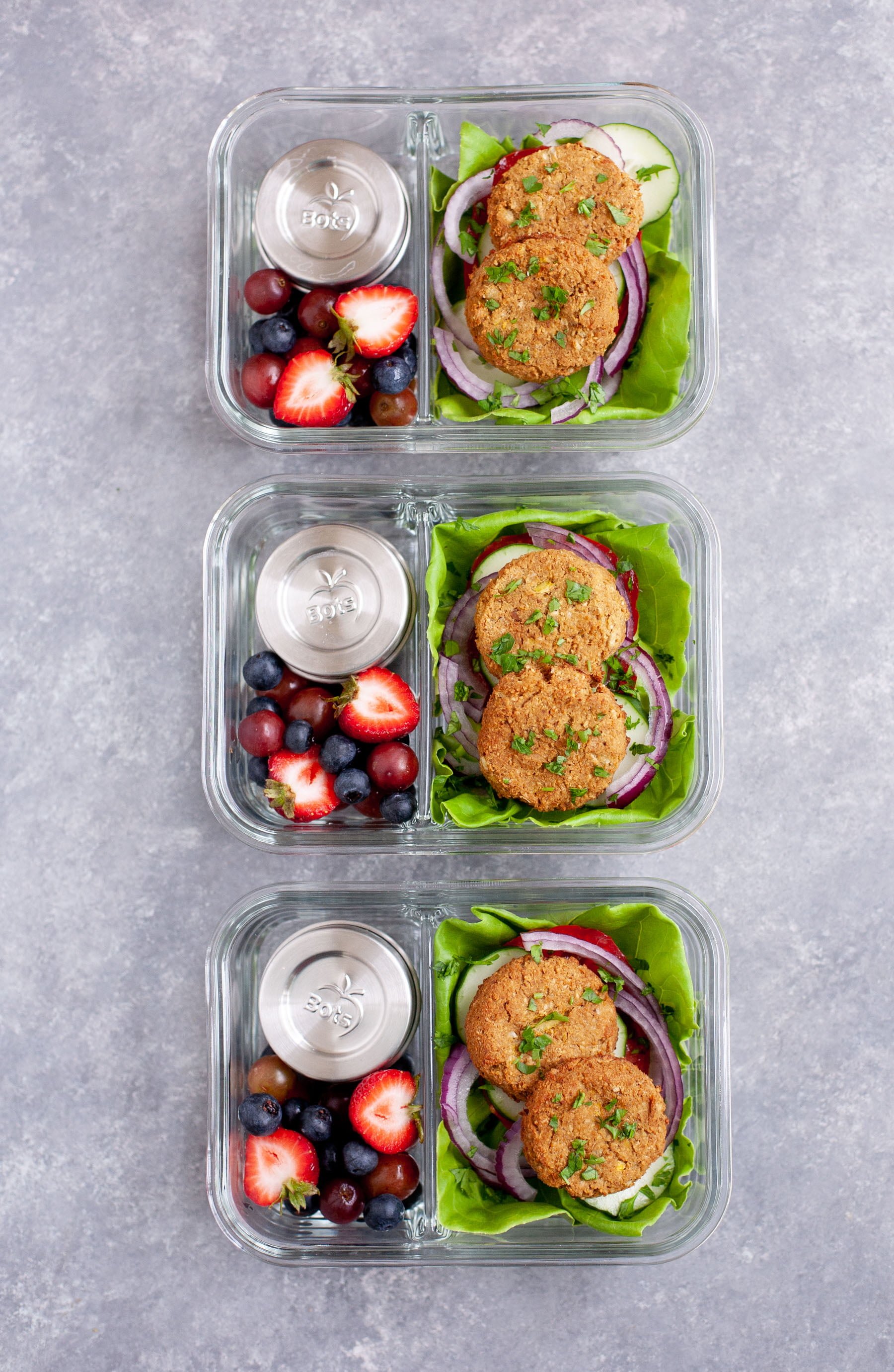 Meal Prep Baked Falafel Lettuce Wraps packed into glass lunch containers with mixed berries and small containers of tahini sauce