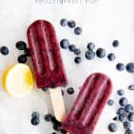 Blueberry Lemonade Frozen Fruit Pops on a bed of crushed ice, surrounded by blueberries and a cut lemon