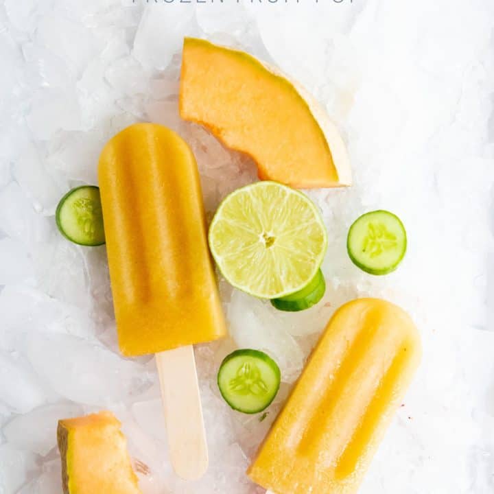 Cucumber Cantaloupe Frozen Fruit Pops on a bed of crushed ice, surrounded by melon, cucumber slices, and half a lime