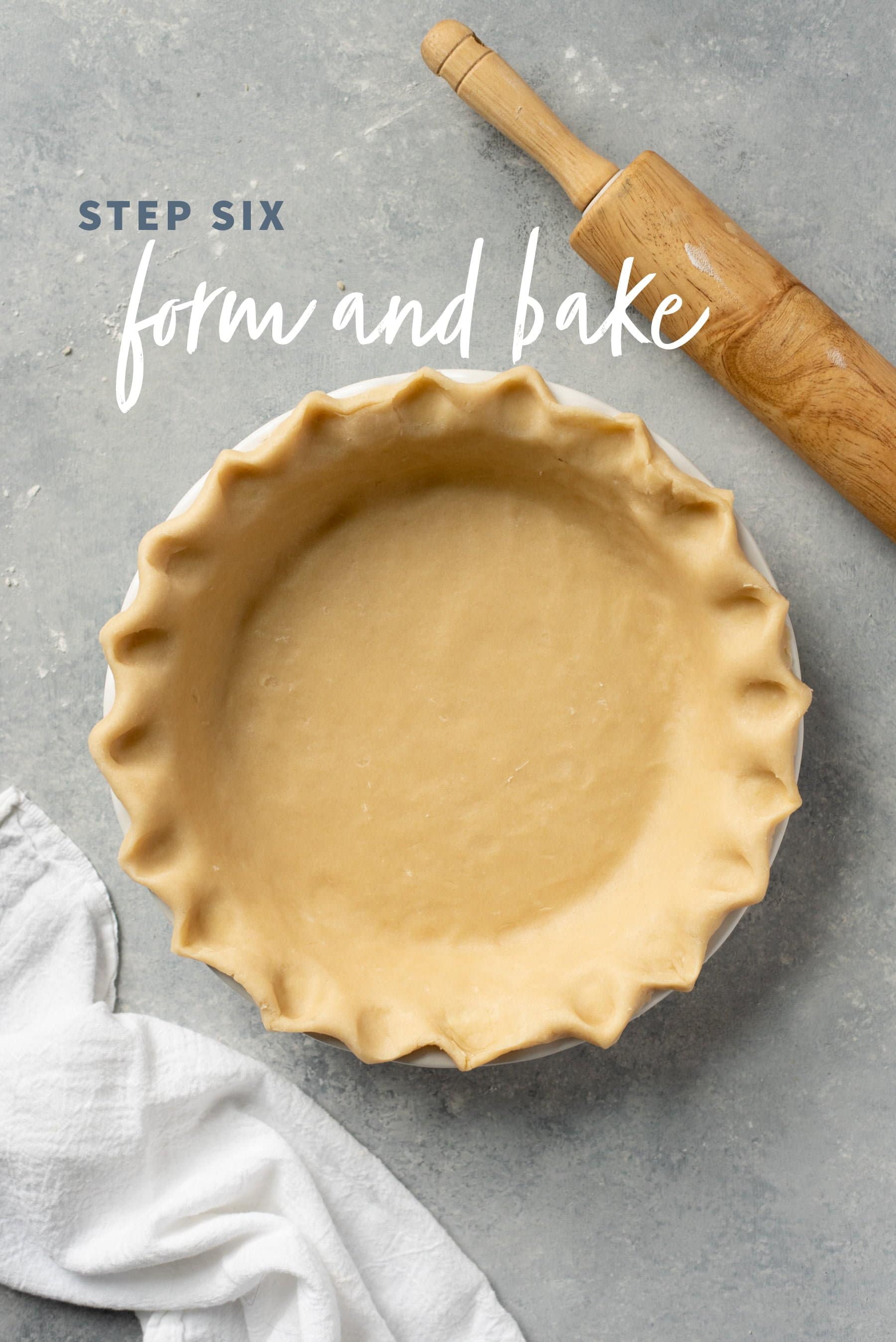 Unbaked pie crust with fluted edges pressed into a pie pan on a gray background