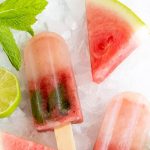 Watermelon Mint Frozen Fruit Pops on a bed of crushed ice, surrounded by watermelon wedges, mint sprigs, and a lime