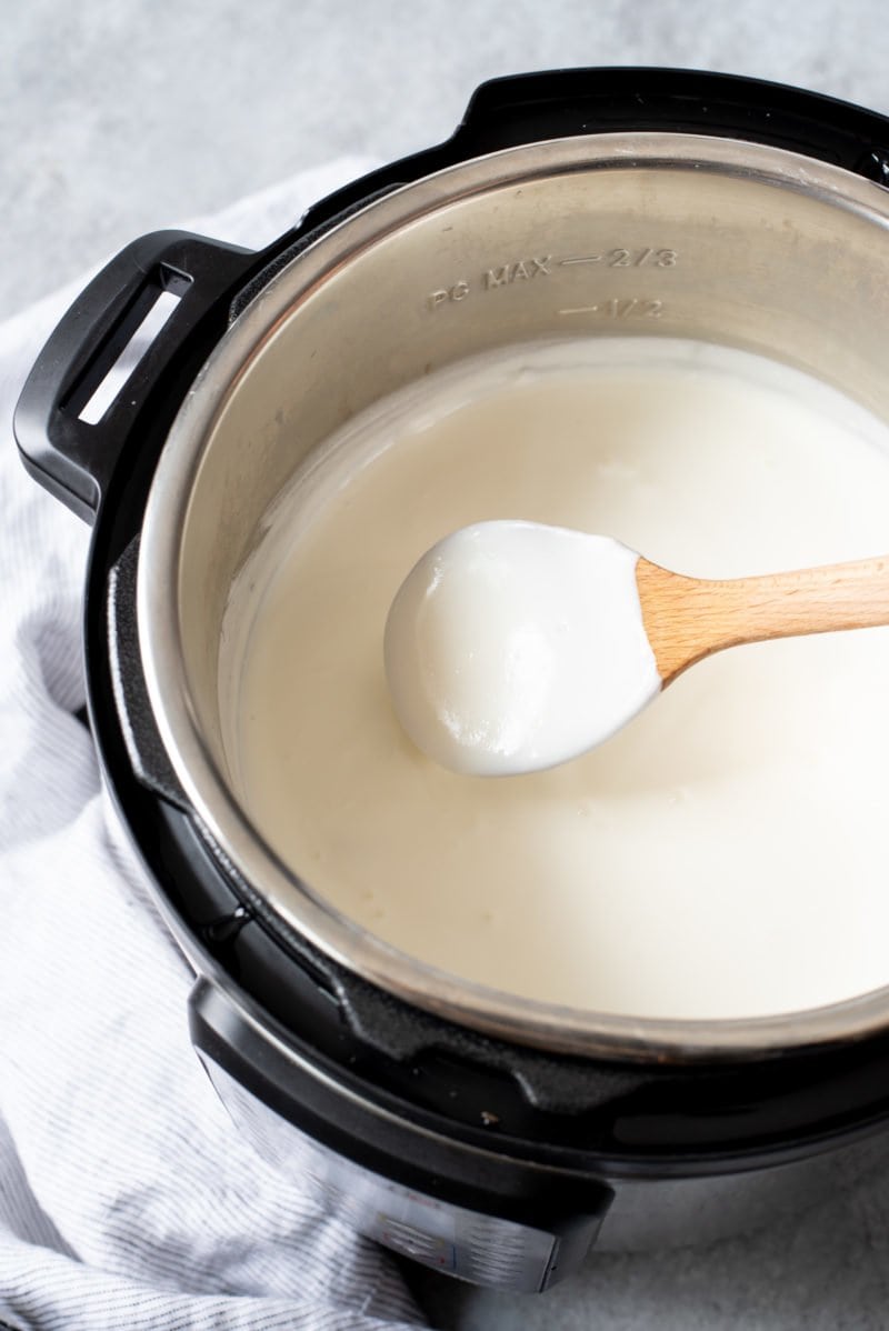 Wooden spoon stirring homemade yogurt in an Instant Pot