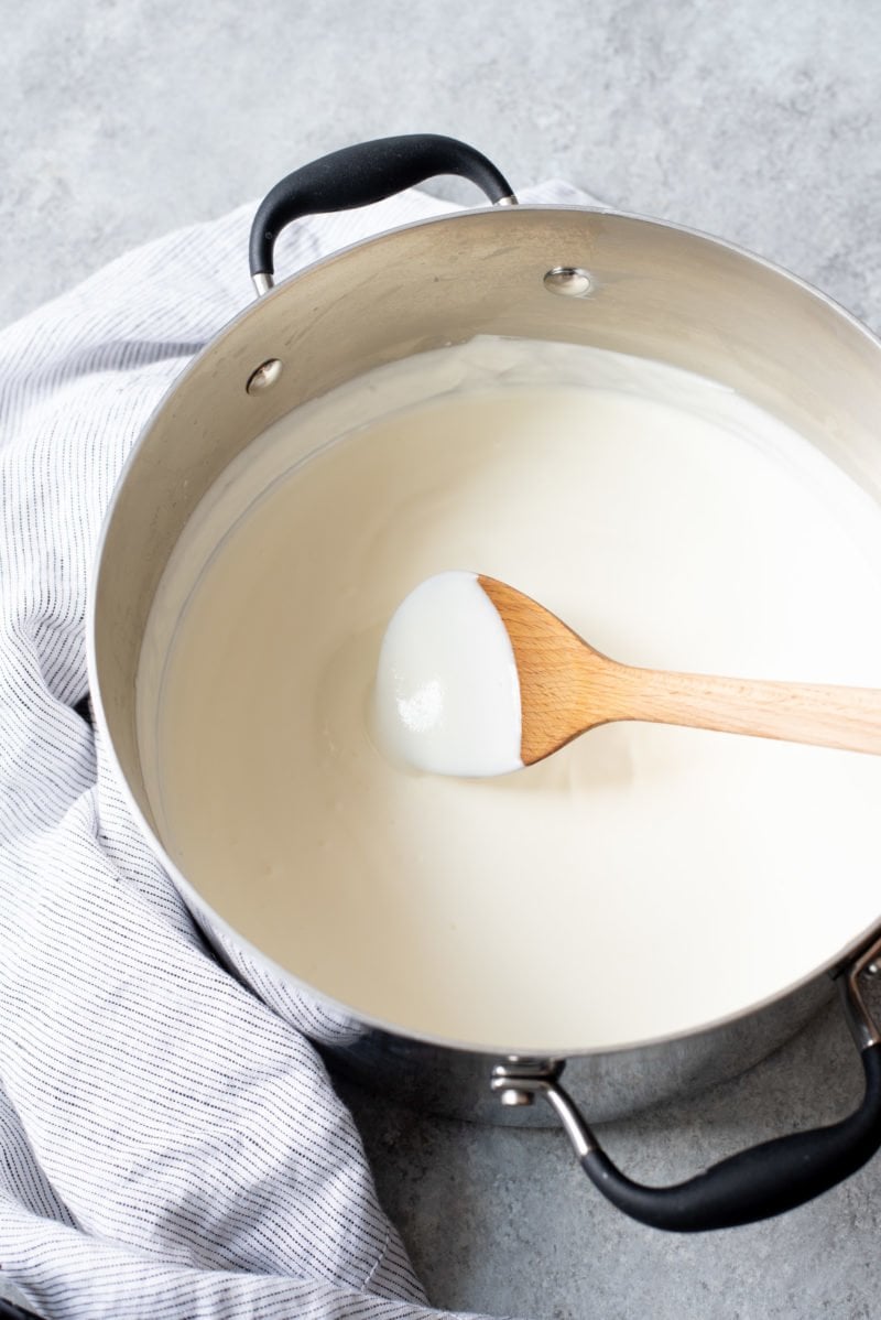 Wooden spoon stirring milk in a soup pot