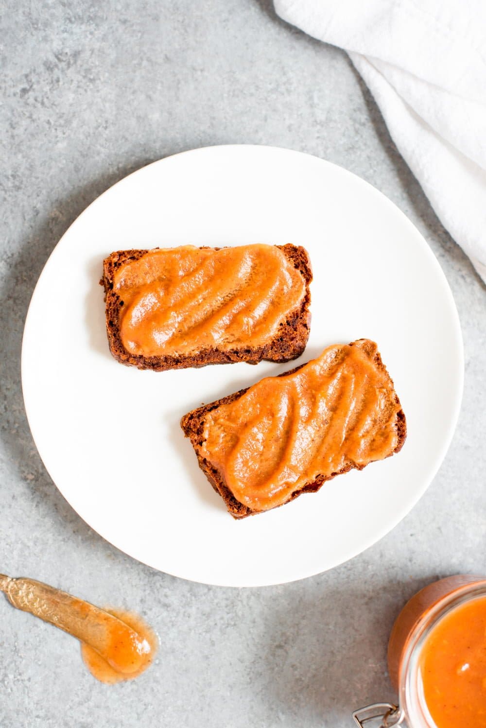 Two slices of Grain-Free Pumpkin Bread topped with apple butter on a white plate