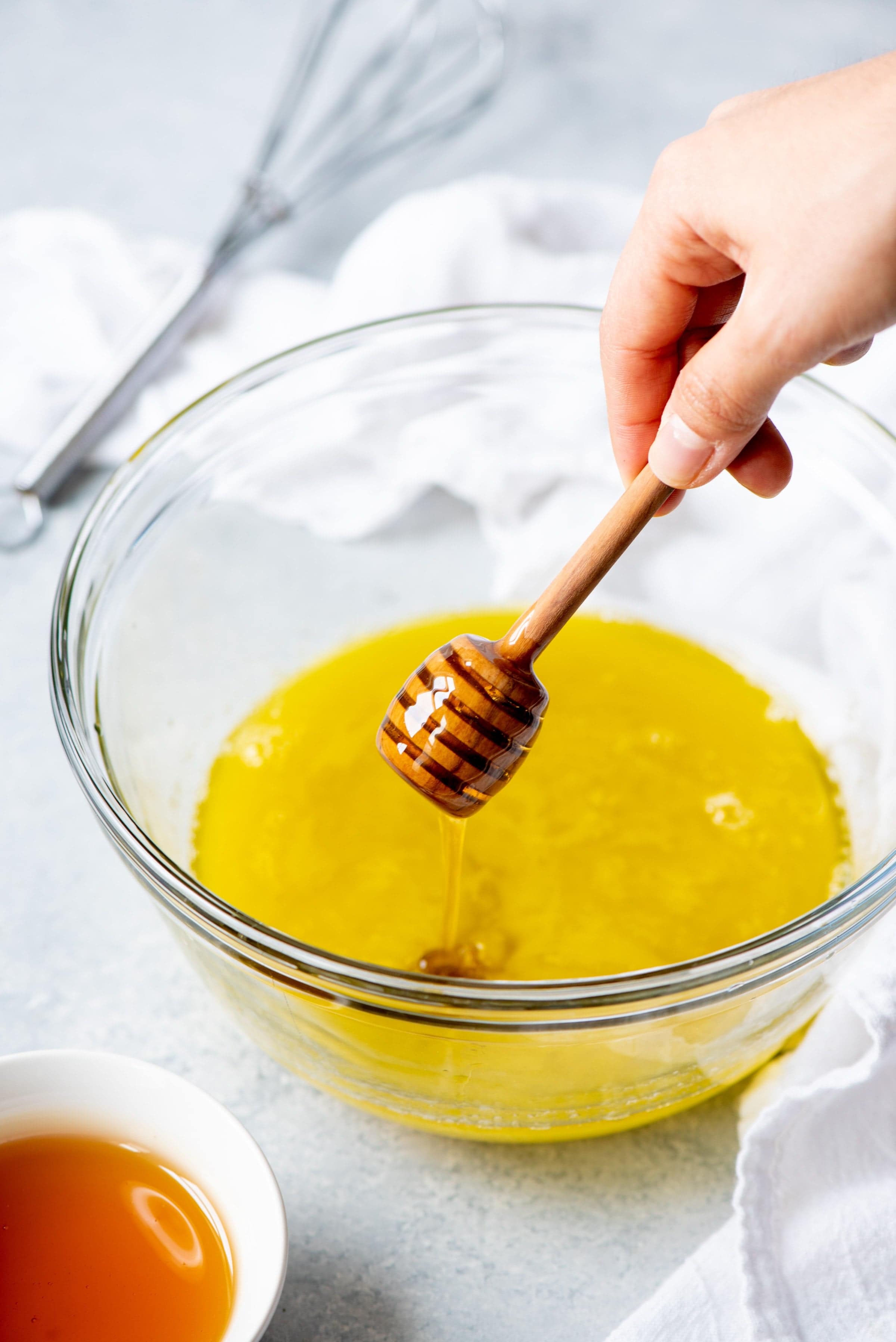 Honey stick drizzling honey into a glass bowl