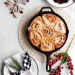 Overhead of a cast iron skillet filled with make-ahead vegan cinnamon rolls drizzled with icing.