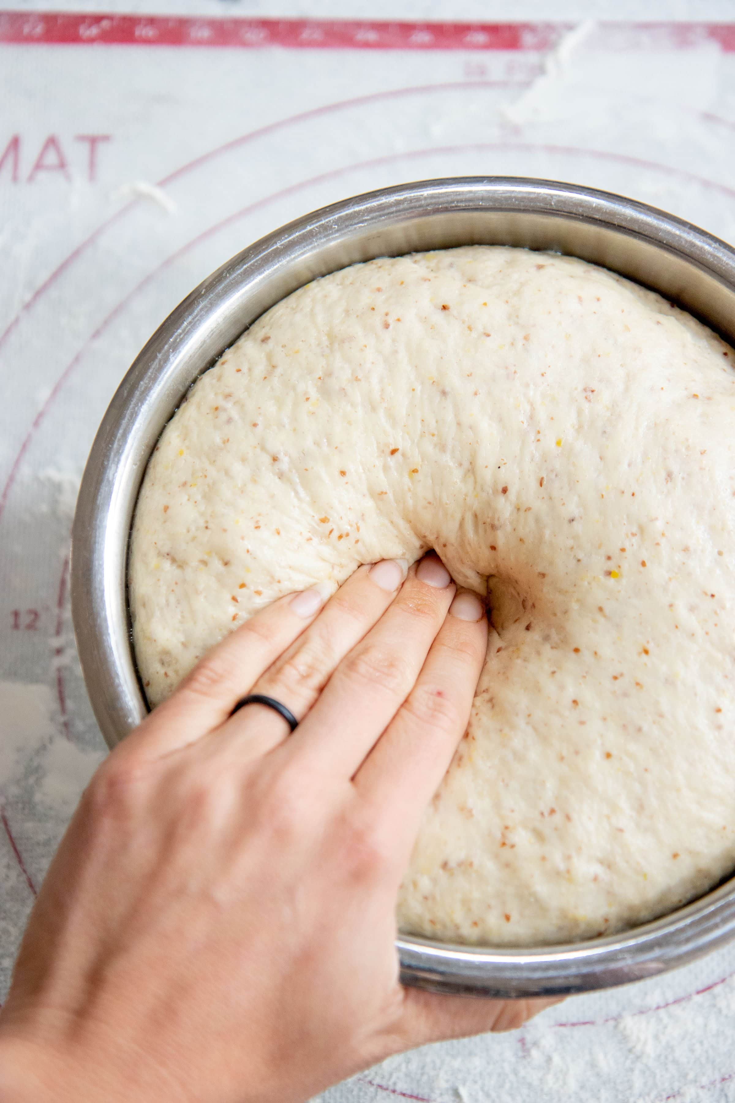 Hand pressing into dough to check the rise.