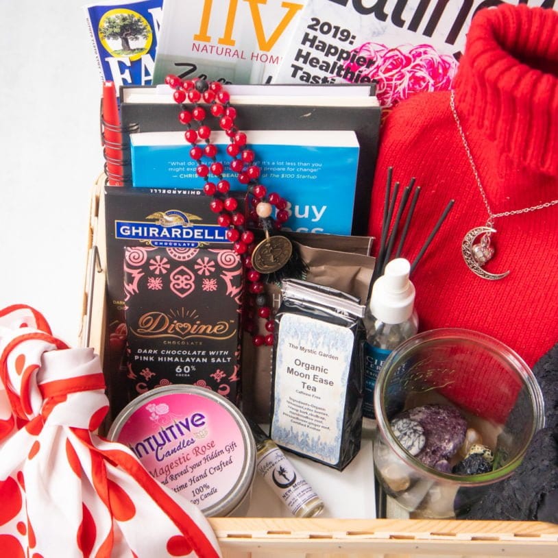 A bleed box, filled with all sorts of goodies - a red and white scarf, a candle, crystals, hot water bottle, magazines, books, a mala, and chocolate.