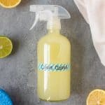 Spray bottle filled with Homemade Citrus All-Purpose Cleaner and labeled "Citrus Cleaner," surrounded by citrus and sponges