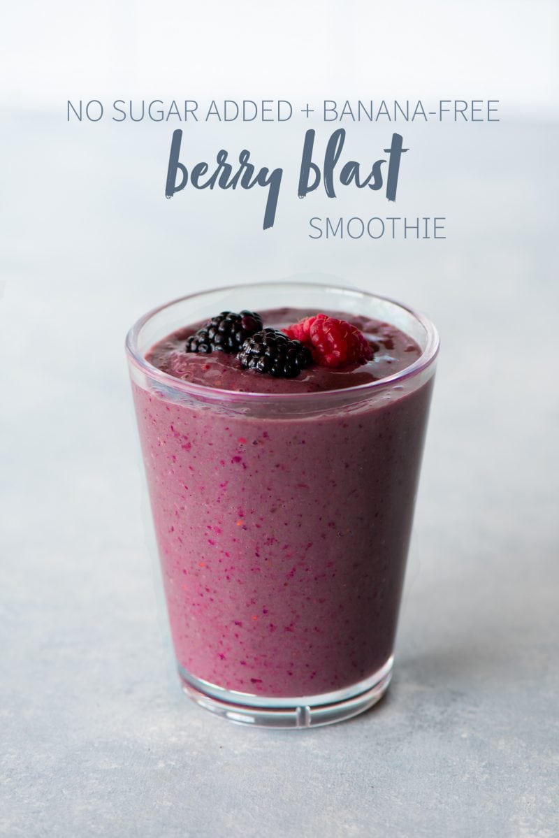 Berry blast smoothie in a clear glass topped with whole berries. A text overlay reads "No Sugar Added + Banana-Free Berry Blast Smoothie."