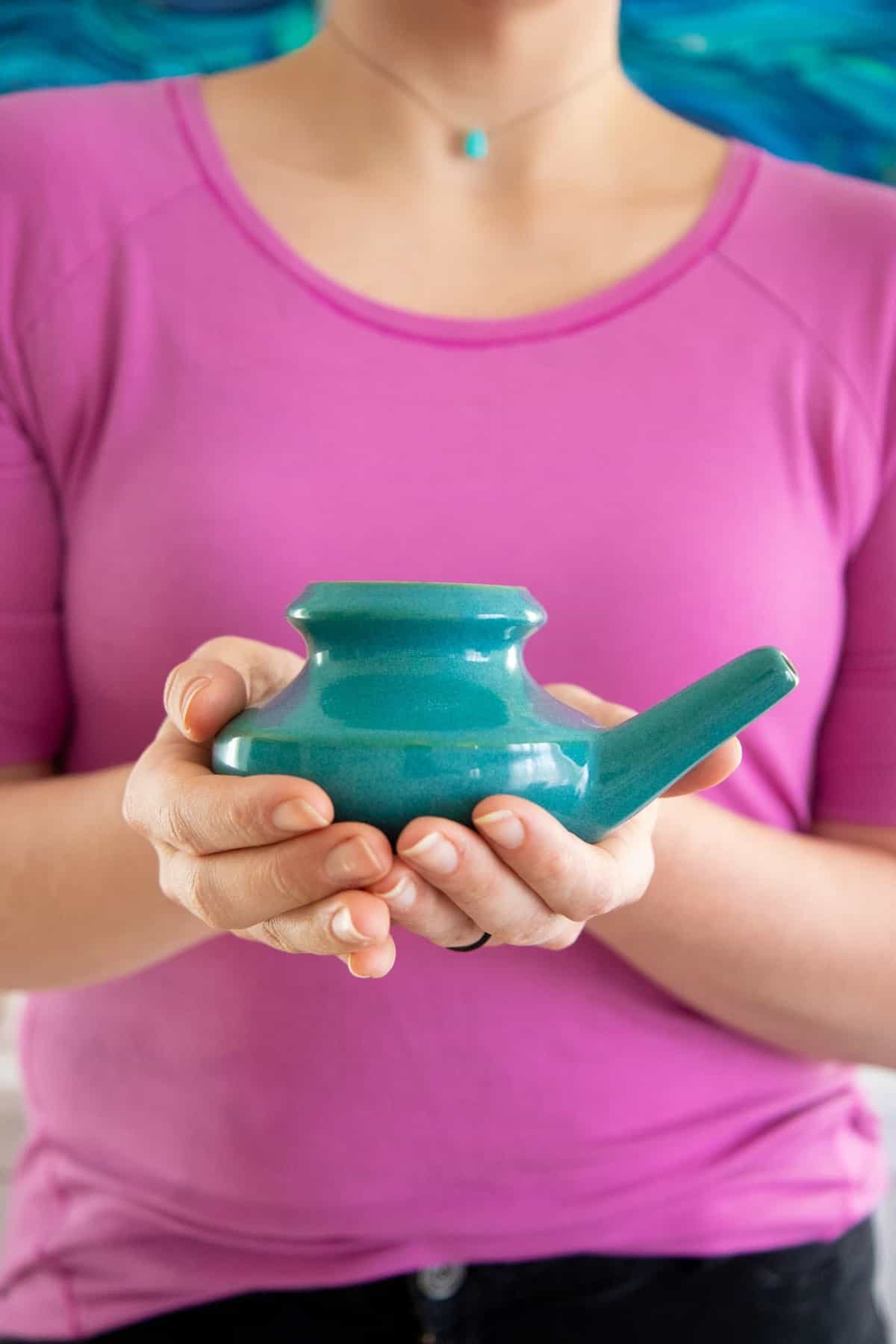 Two hands holding a ceramic neti pot