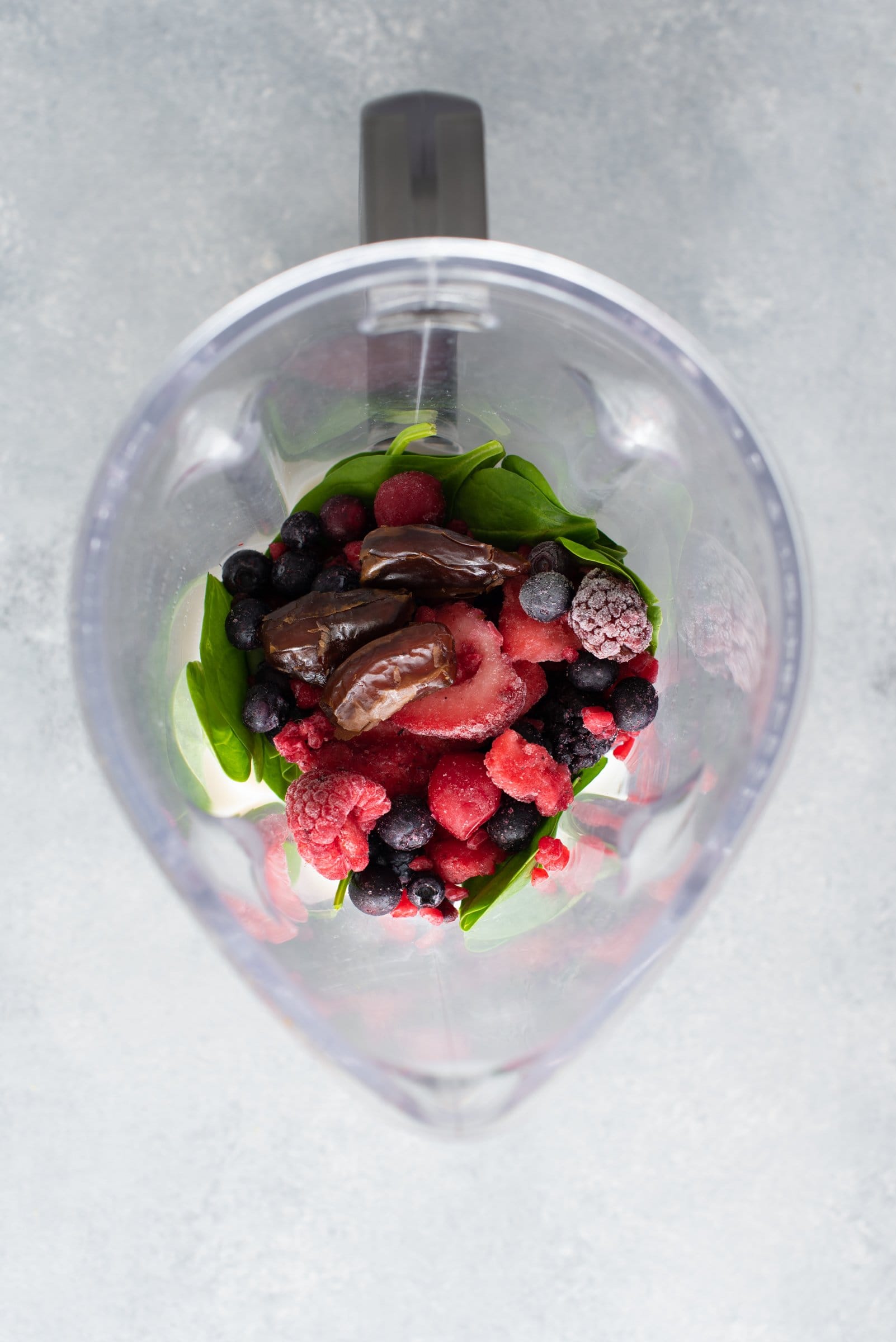 Overhead shot of smoothie ingredients in the carafe of a blender.