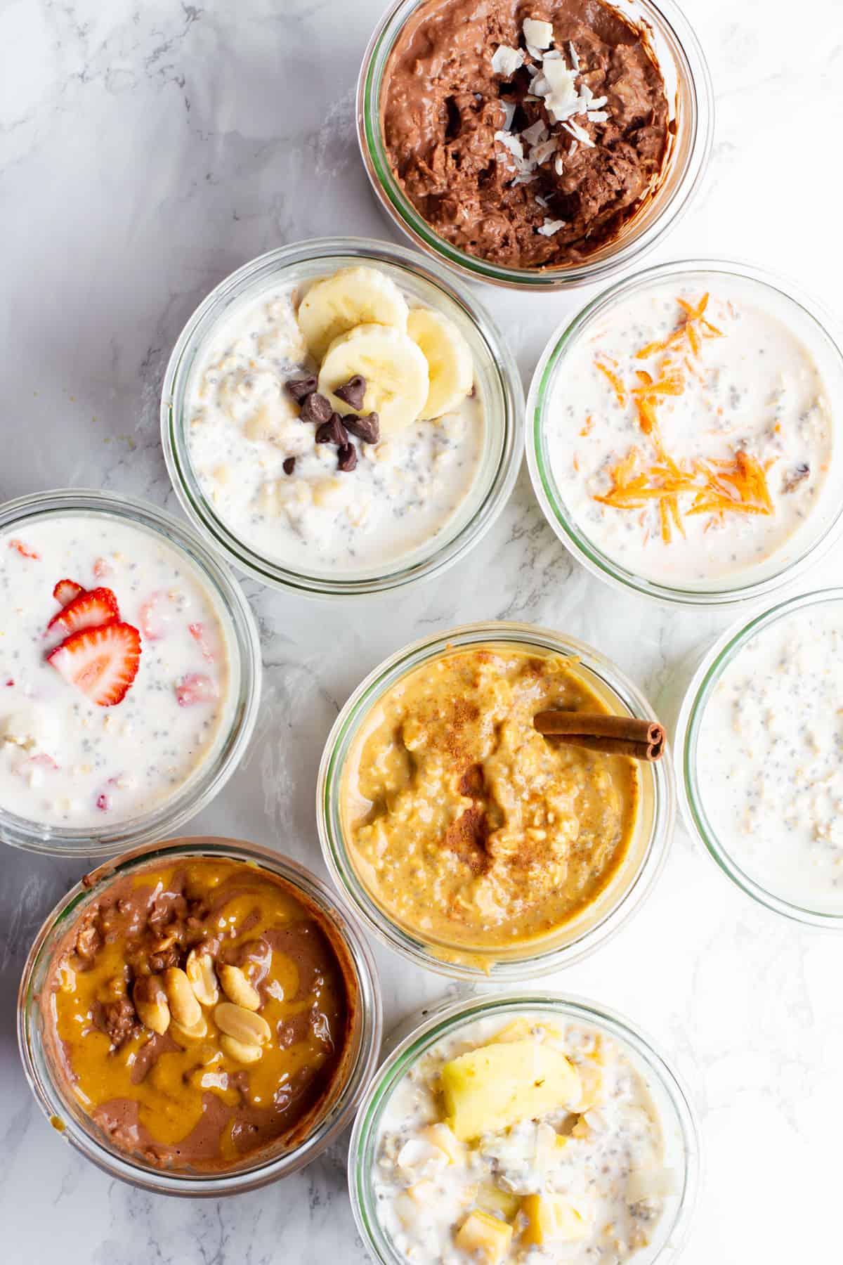 Overhead shot of eight different flavors of overnight oats, each in its own glass jar.